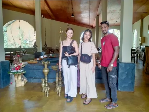 Two guests and their driver-guide in a hall with tall brass oil lamps
