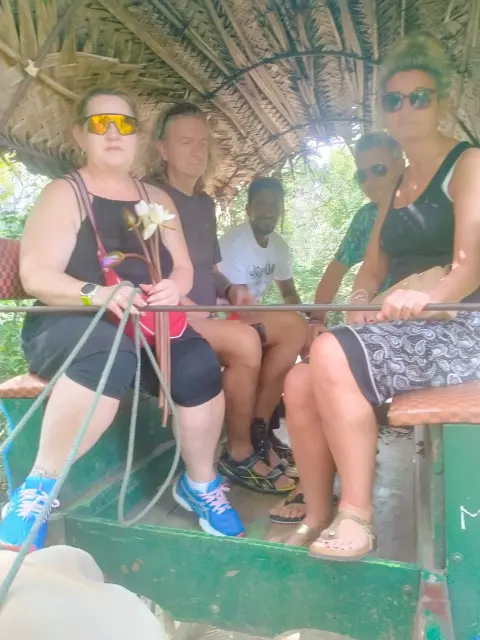Guests sitting in a thatched bullock cart, one holding the reins