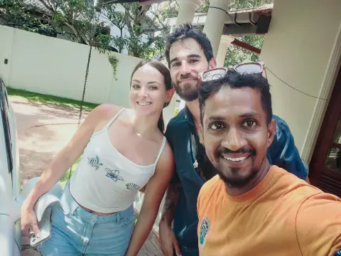 Two guests and their driver-guide taking a selfie beside a car outside a building