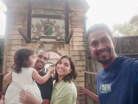 A family with a toddler and their driver-guide taking a selfie in front of an old gateway topped with a coat of arms