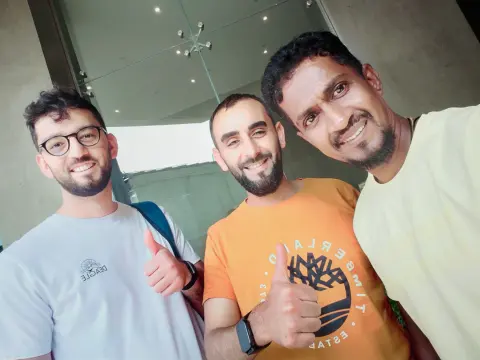 Two guests and their driver-guide giving a thumbs-up indoors