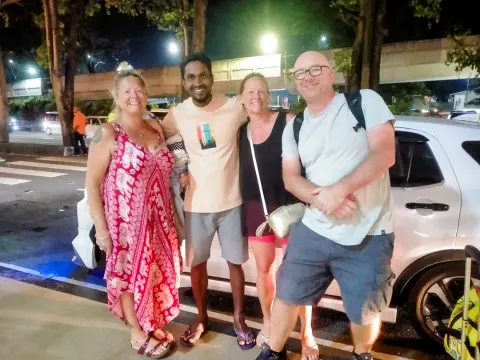 Three guests and their driver-guide standing beside a white car at night