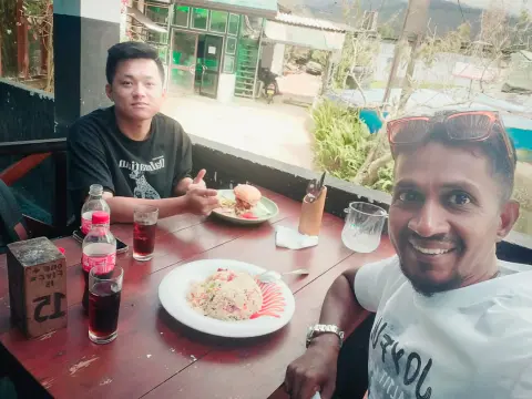 A guest at a restaurant table with fried rice and a burger while their driver-guide takes a selfie