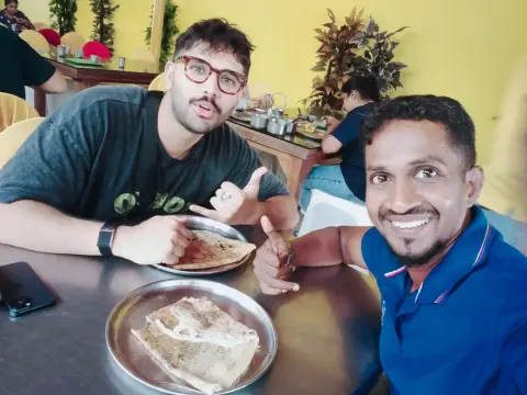 A guest at a restaurant table with a plate of flatbread, their driver-guide smiling beside them