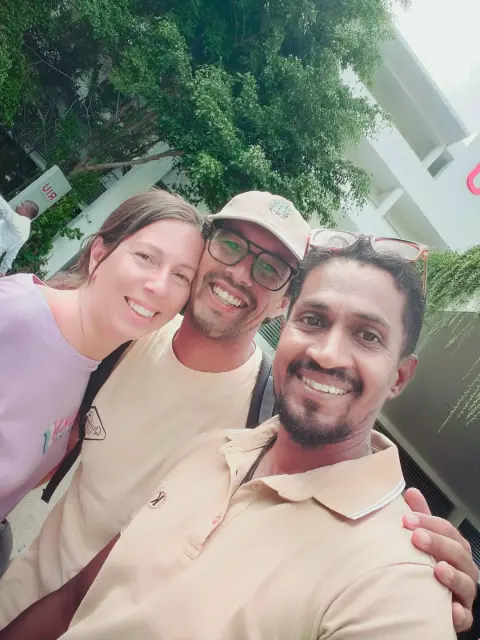 Two guests and their driver-guide taking a selfie under green trees