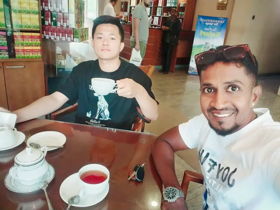 A guest sipping tea at a tea shop table while their driver-guide takes a selfie