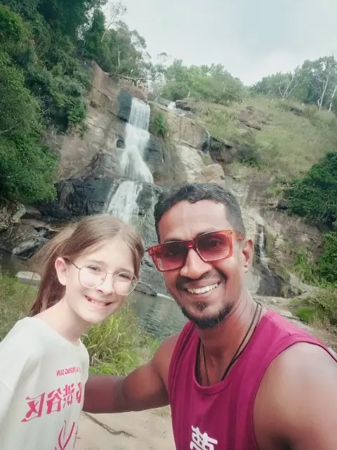 A young guest and their driver-guide taking a selfie in front of a waterfall
