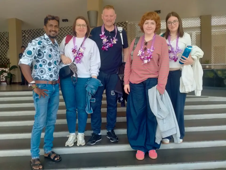 Four guests wearing orchid garlands in a hotel lobby with their driver-guide