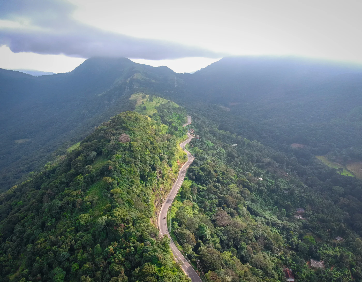 Aerial view of a road winding along a forested ridge between mountains