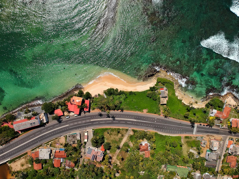 Aerial view of a coastal road running beside a sandy beach and turquoise sea